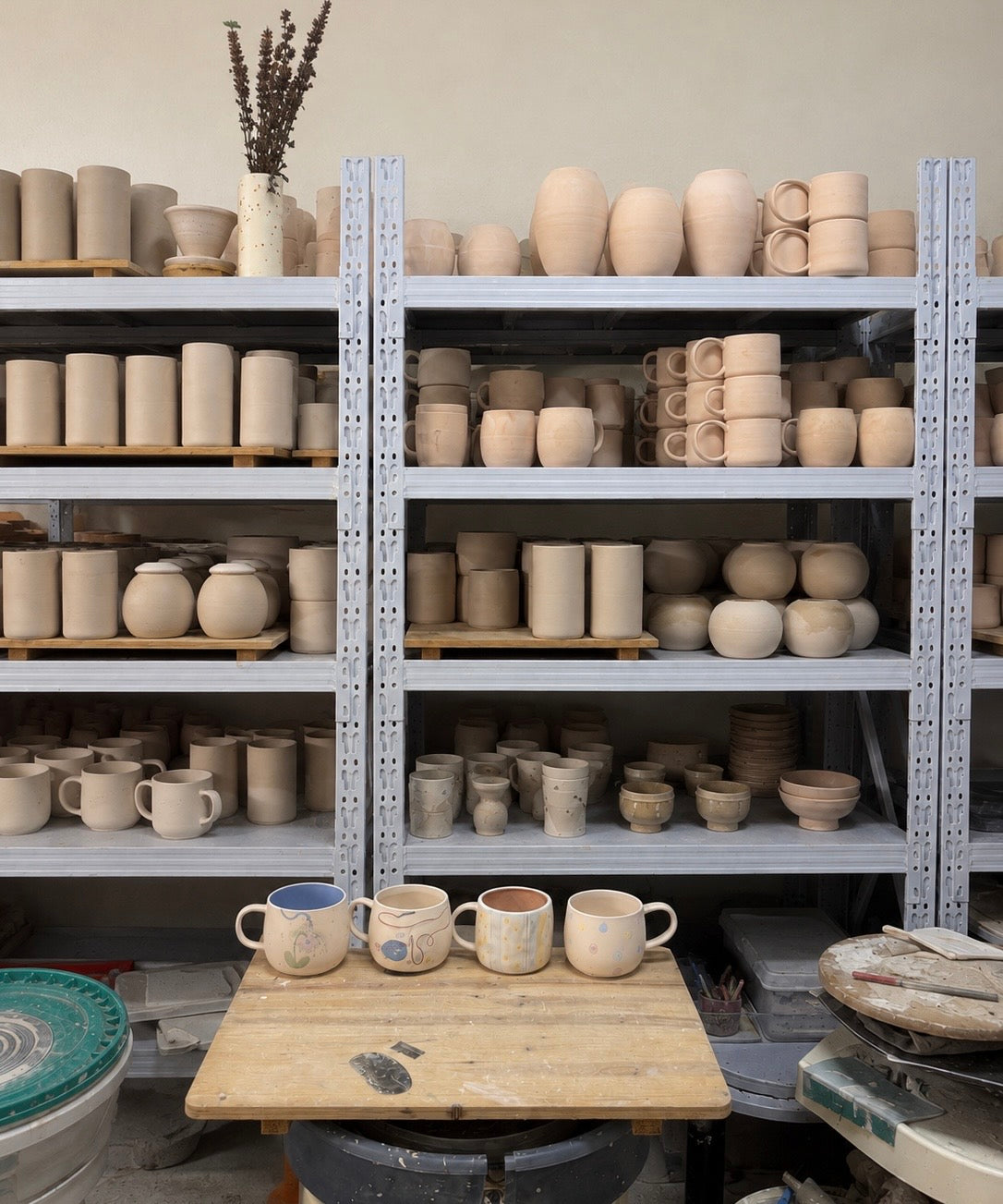 Étagères de l’atelier remplies de tasses et de pièces en céramique avant décoration