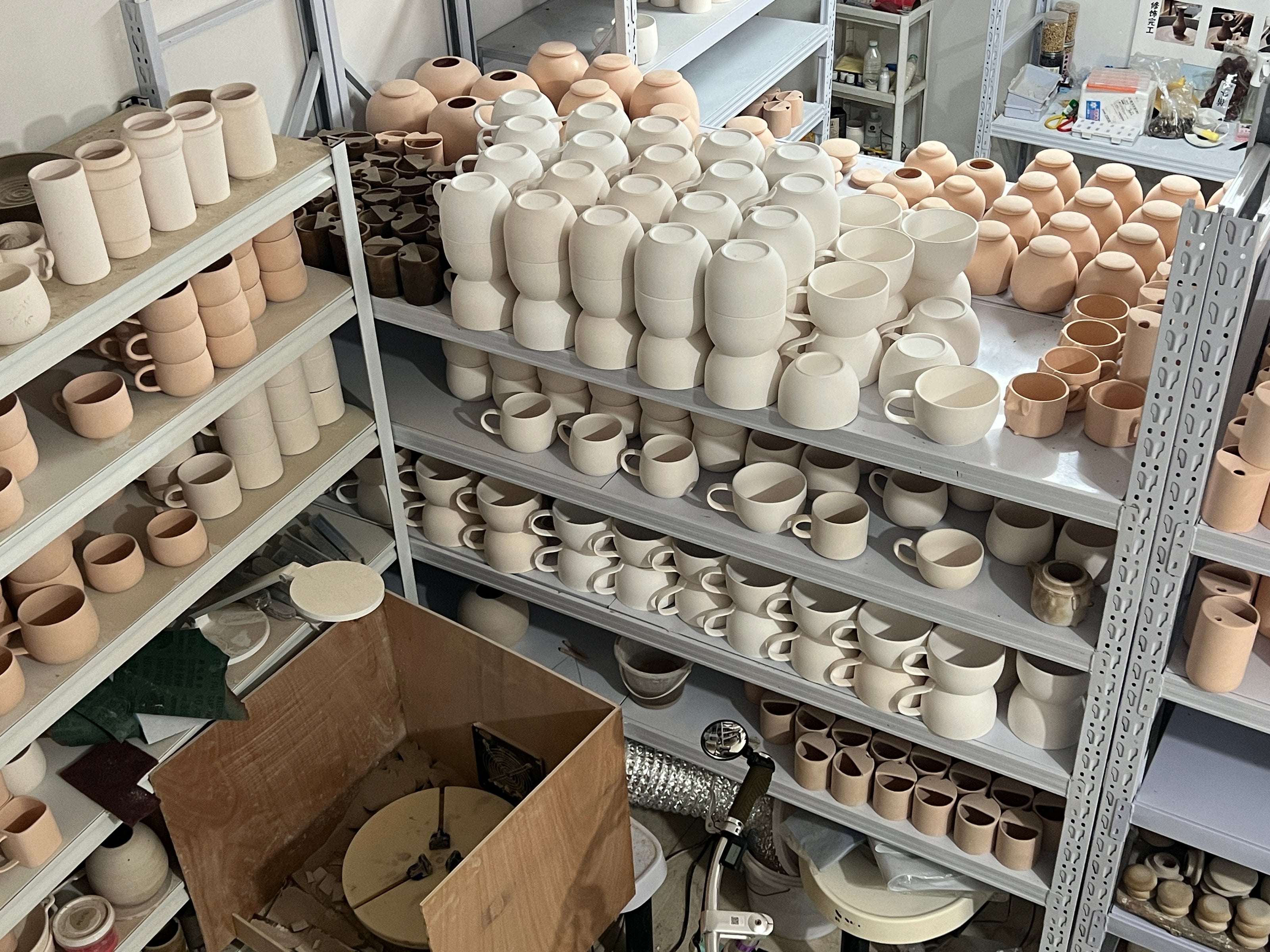 Atelier Maison Scott avec des tasses, bols et pièces en céramique brute avant peinture et personnalisation
